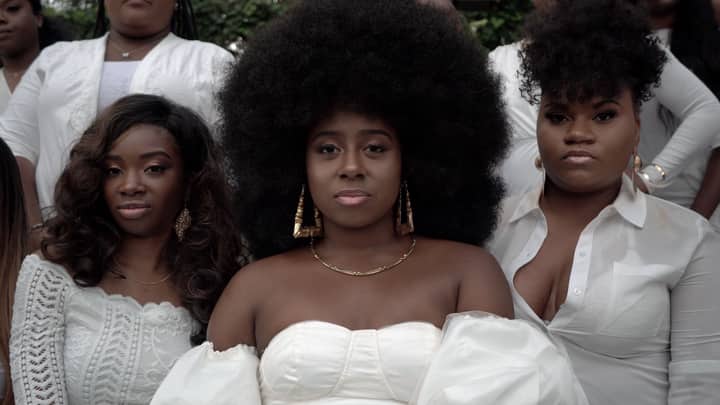 Stylish black women with afro hair posing confidently in elegant white outfits.