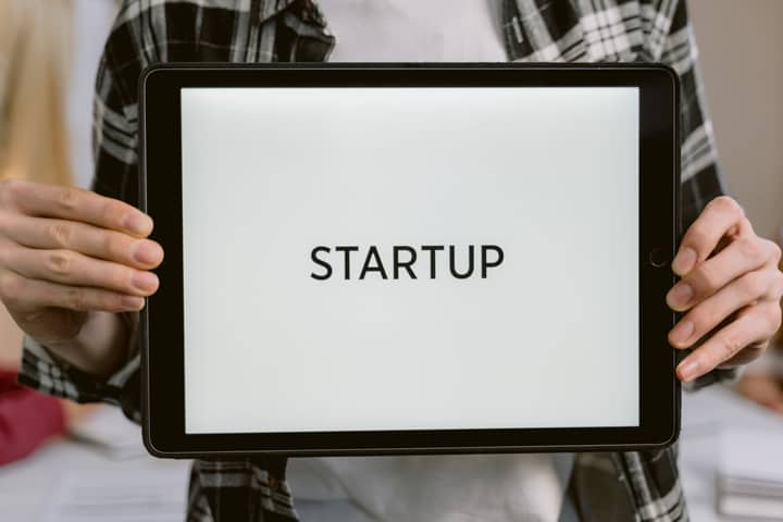 Person holding a digital tablet displaying the word 'STARTUP', representing new business concepts.