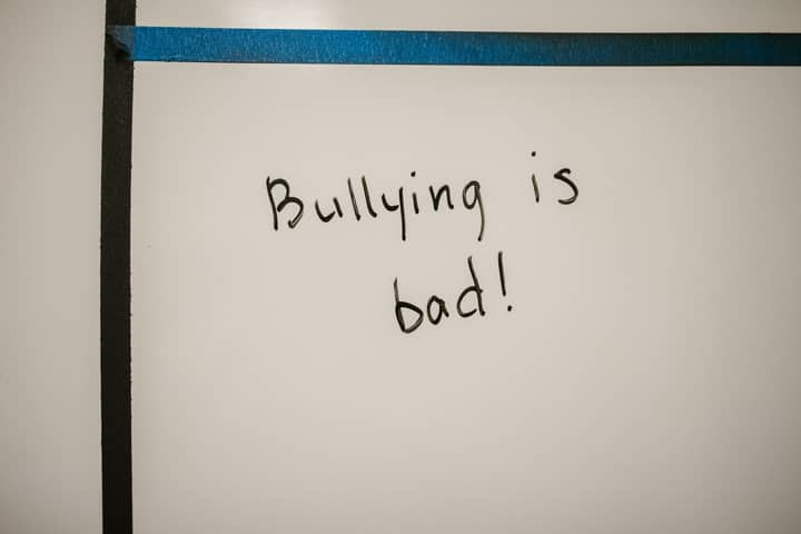 A handwritten message on a whiteboard promoting anti-bullying awareness and prevention.