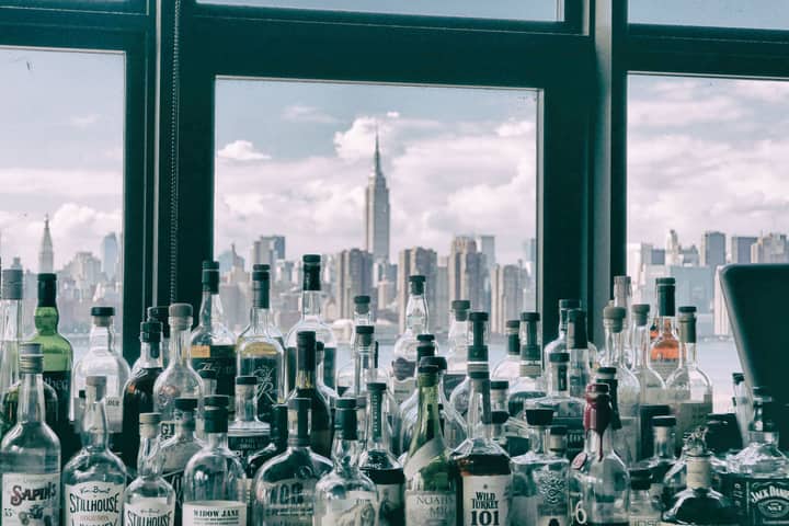 Bottles in a bar with a stunning view of the New York City skyline, showcasing the Empire State Building.