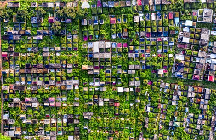 Drone shot of a green cemetery in Tangerang, Indonesia, showcasing arranged tombstones and mausoleums.