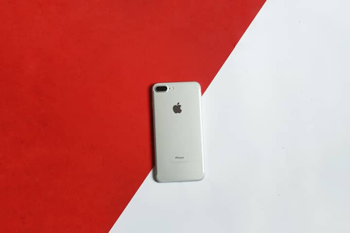 A silver smartphone placed on a contrasting red and white background captured from above.