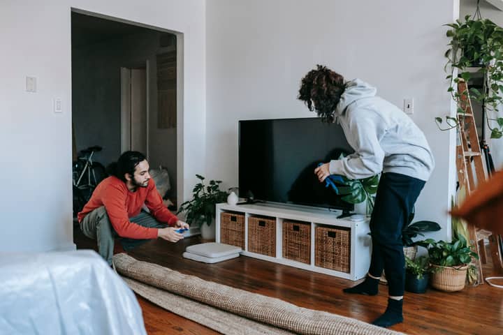 A couple organizing their living space with modern interior design elements and household items.