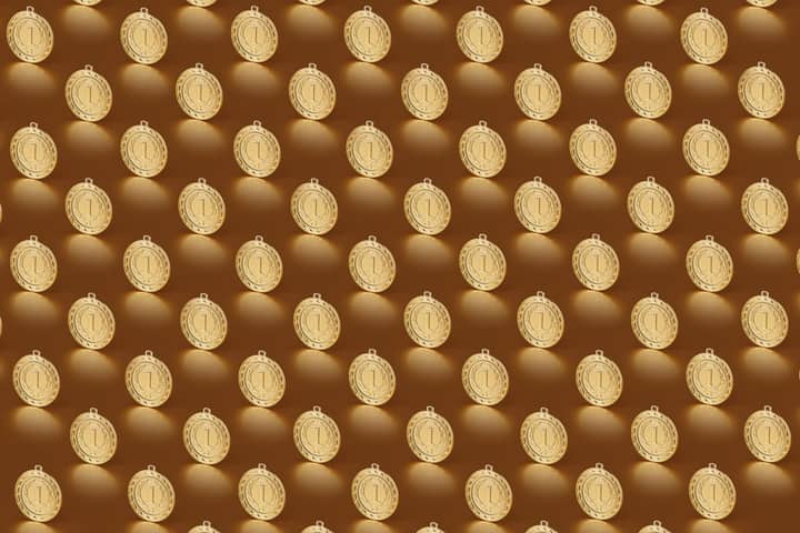 Multiple gold medals arranged in a repeating pattern on a brown backdrop.