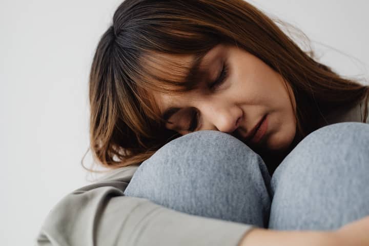 Serene close-up of a woman resting indoors, eyes closed, conveying peace and relaxation.