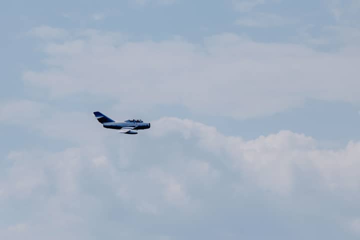 Creative design of modern fighter aircraft flying in light sky with fluffy clouds in daylight