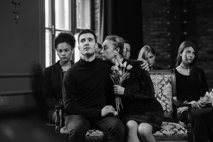 A touching scene of people embracing during a solemn memorial service, conveying sorrow and compassion.