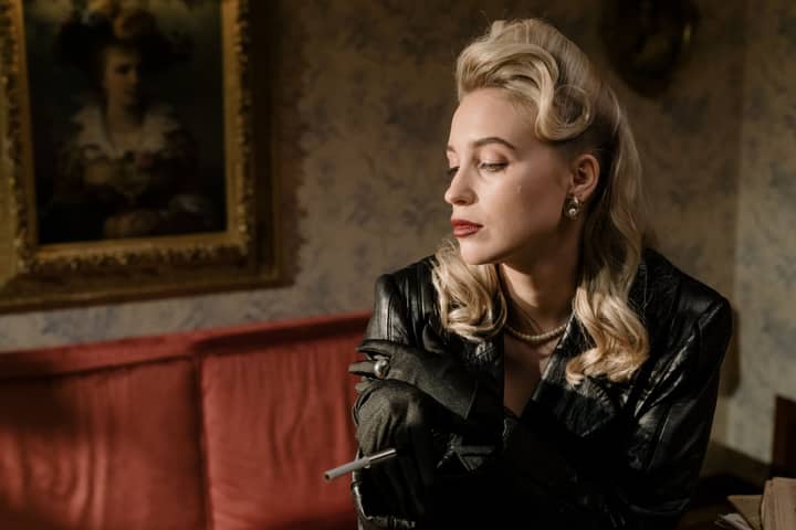 A stylish woman with vintage glamour and elegance, indoors in a noir setting.