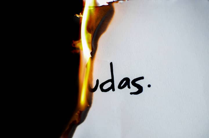 A piece of paper with handwritten text 'udas' partially engulfed in flames.
