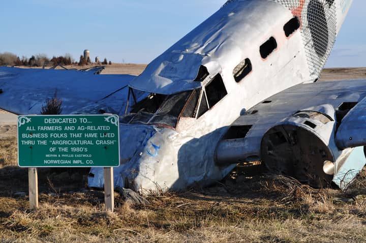 A wrecked airplane amid an open farmland, symbolizing the agricultural crash of the 1980s.