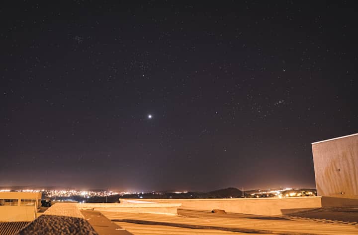 A stunning starry night sky over Goiânia, Brazil, captured from a rooftop with city lights visible.