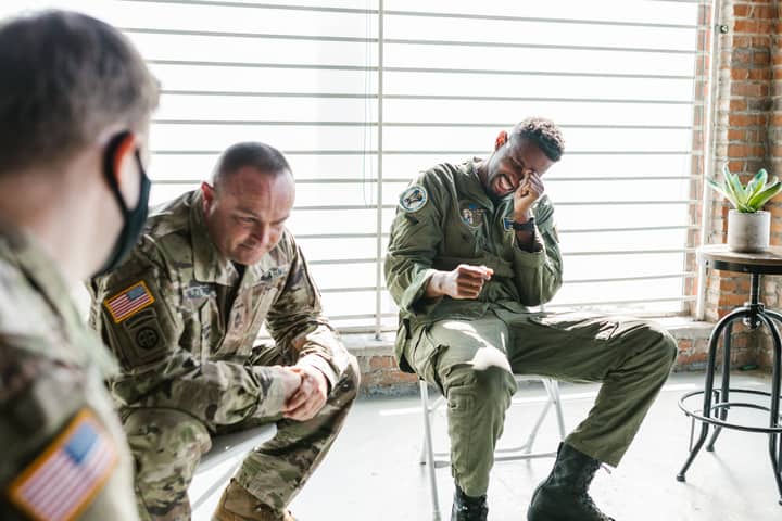 Veterans share a light moment during a group therapy session, indoors.