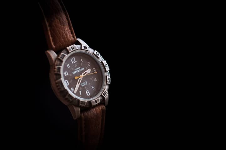 A detailed shot of a Timex Expedition wristwatch with a leather strap against a black backdrop.