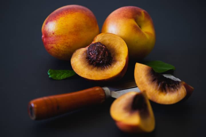 Vibrant fresh peaches sliced with a knife. Perfect for summer fruit concepts.