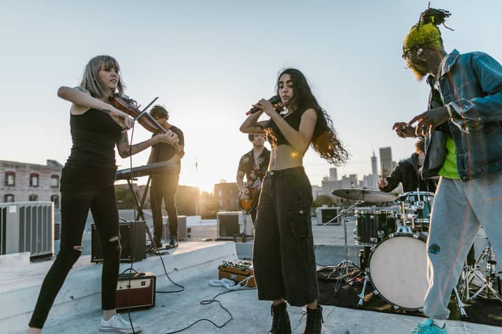 A lively band performs on a rooftop at sunset, capturing a vibrant musical atmosphere.