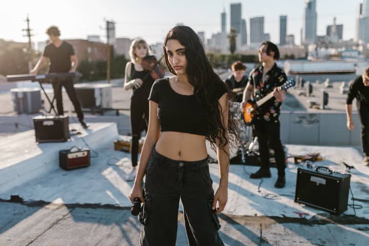Energetic band playing live music on a rooftop with city skyline backdrop at sunset.