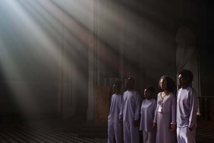 A choir of adults singing under sunbeams in a cathedral, creating a spiritual atmosphere.
