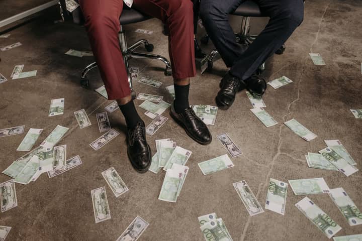 Two people in an office with euro banknotes scattered on the floor, showcasing a financial theme.