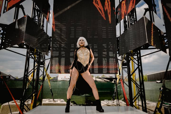 A stylish female performer in bold attire striking a pose on an outdoor stage.