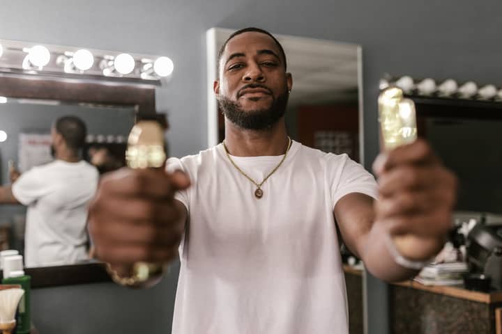 Confident man holding clippers in a barbershop, ready for grooming session.