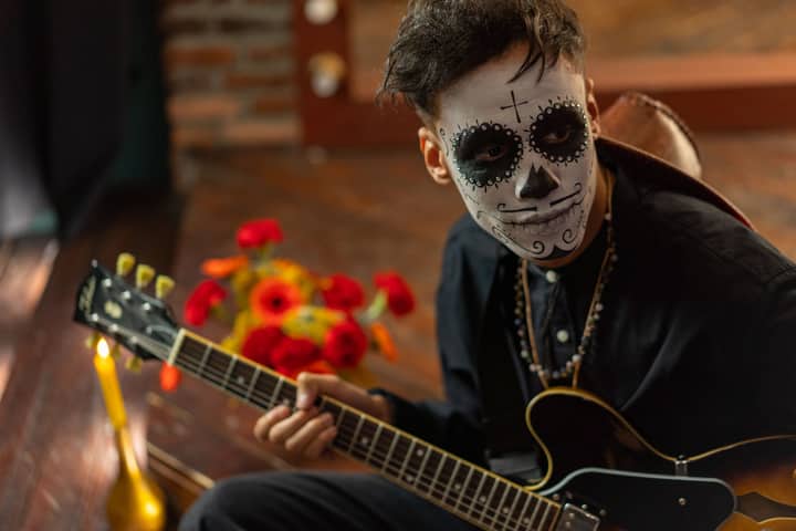 Musician with face paint playing guitar on Day of the Dead celebration.