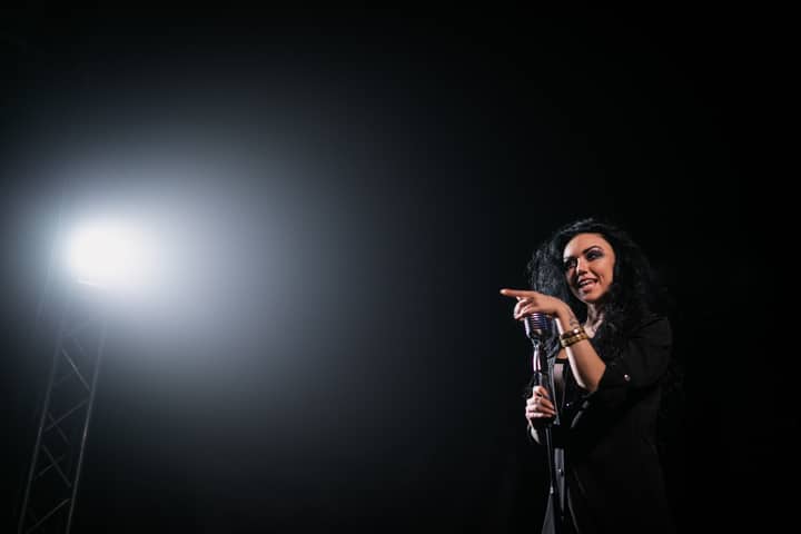 Live performance of a female singer on stage under a spotlight, exuding energy and charisma.