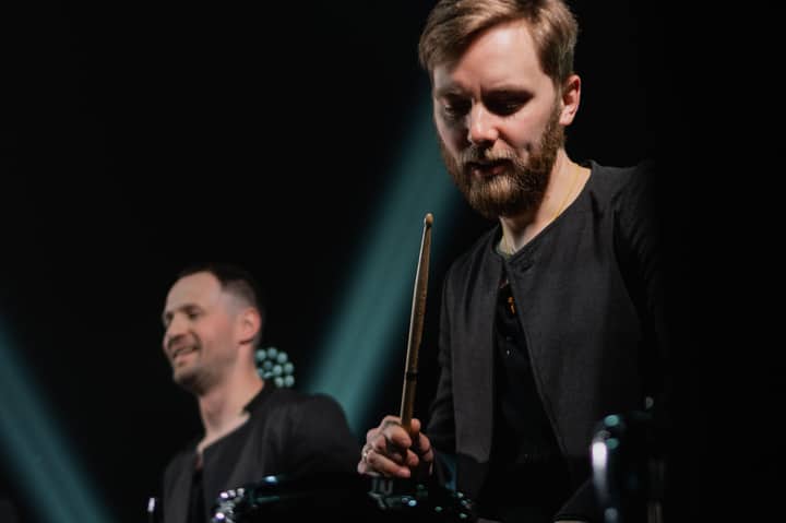 Dynamic shot of a drummer and bandmate on stage during an electrifying live concert.