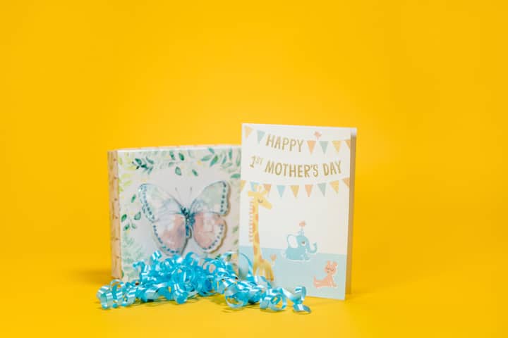 Vibrant Mother's Day card and gift box with butterfly design on bright yellow background.