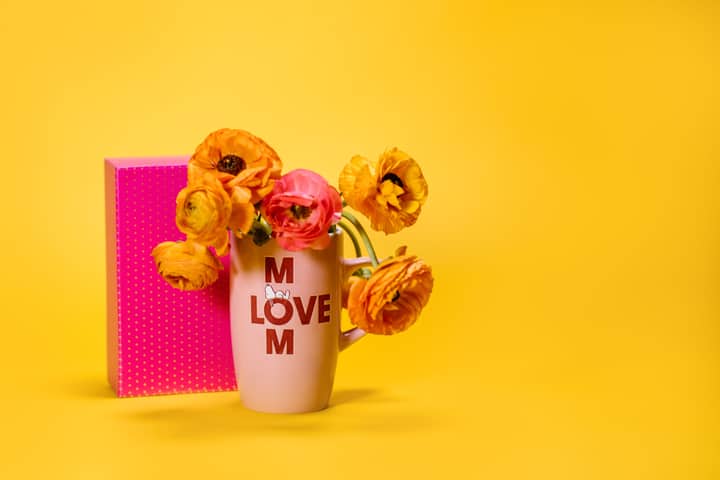 Colorful bouquet in a mom-themed mug on a bright yellow background, perfect for Mother's Day greetings.