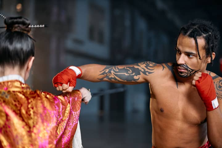 Two martial artists engage in combat, showcasing traditional attire and tattoos.