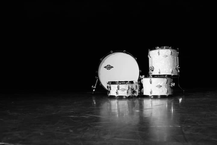 Classic black and white photo of a drum set in a dramatic, moody setting.