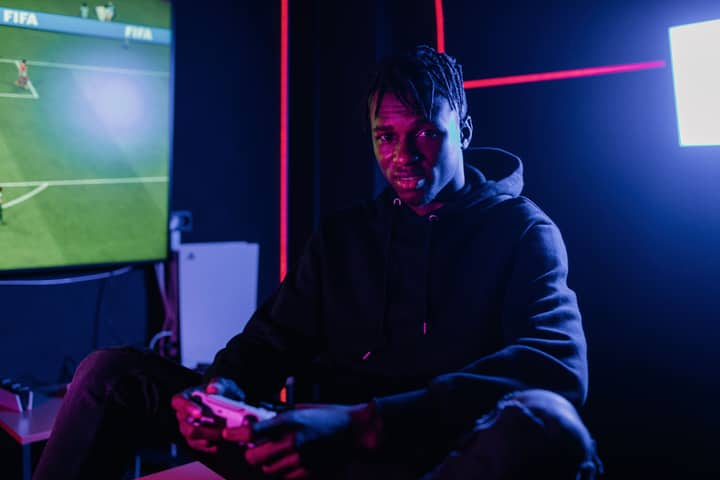 A man playing video games at night in a neon-lit room, immersed in leisure and fun.