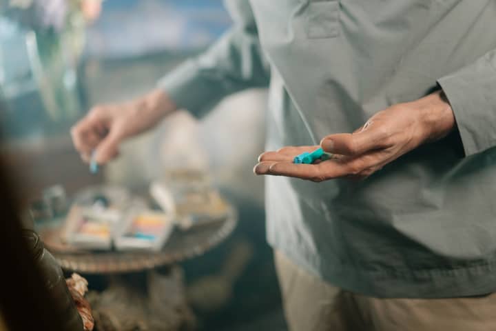 An artist holding pastel crayons, preparing for a creative session with blurred background.