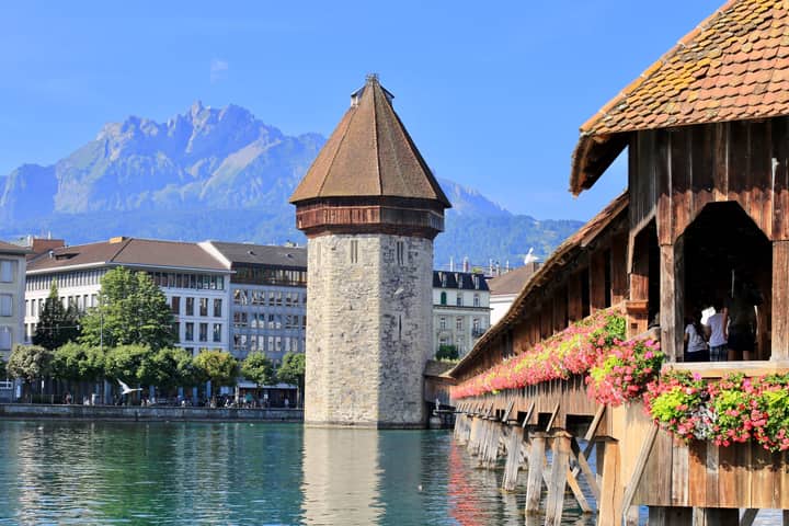 View of the iconic Chapel Bridge and Water Tower in Lucerne, Switzerland on a sunny day.
