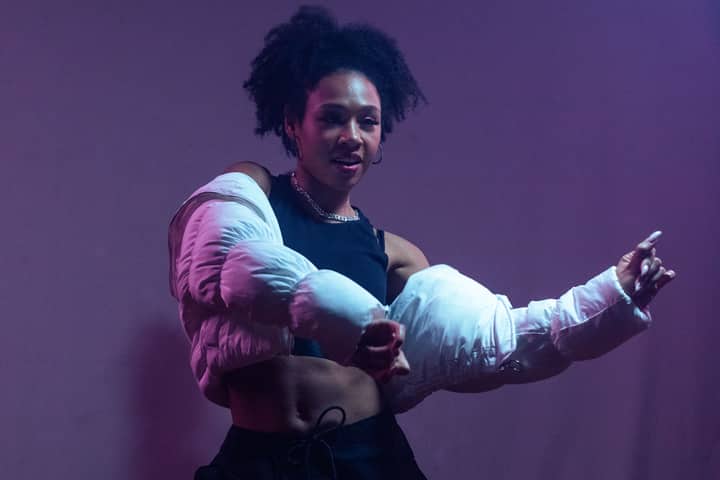 A dynamic African American woman performing hip hop dance moves in stylish attire.
