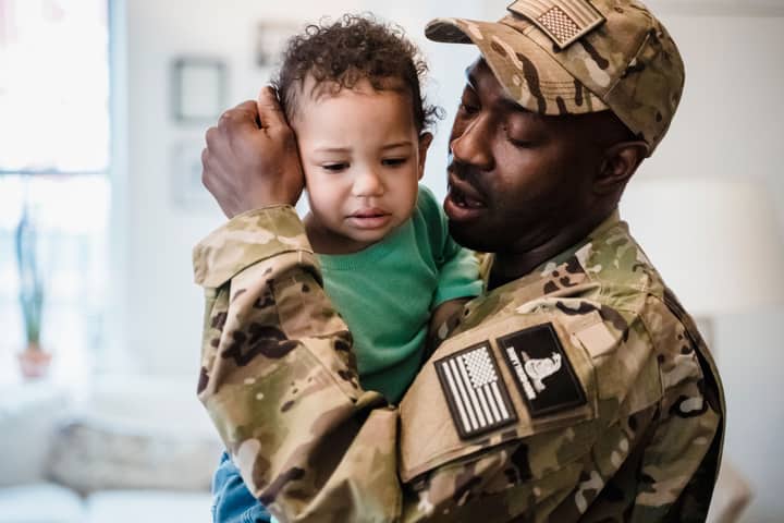 A loving moment between a soldier and his child captured indoors.