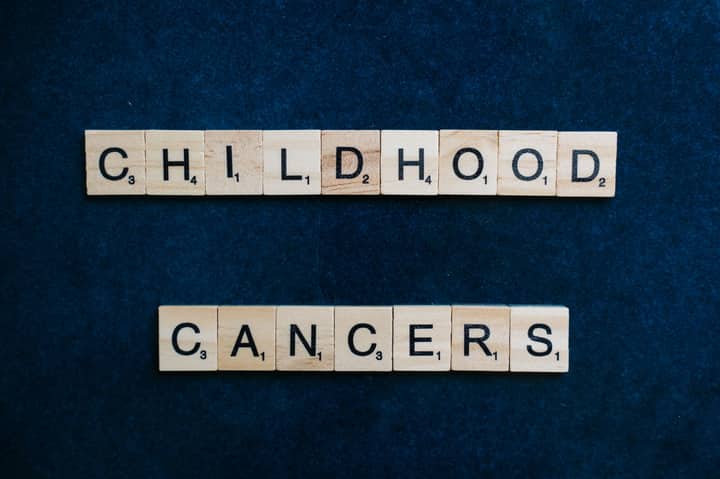 Scrabble tiles arranged to spell 'Childhood Cancers' on a dark blue background.