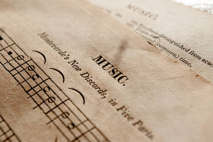 Detailed view of antique music sheets featuring notes and Monteverde's New Discords in sepia tone.