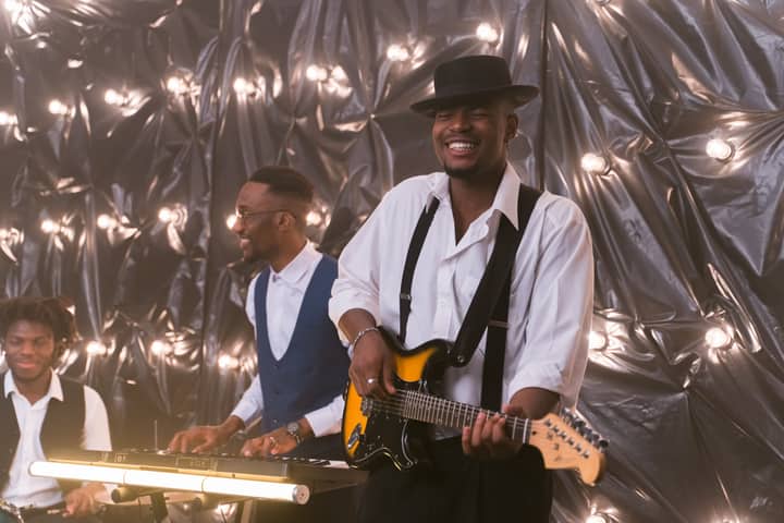 Lively music band performing with guitar and piano under stage lights.
