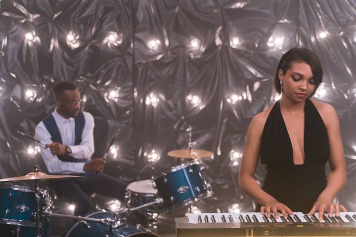A jazz band featuring a pianist and drummer performing on stage with moody lighting.