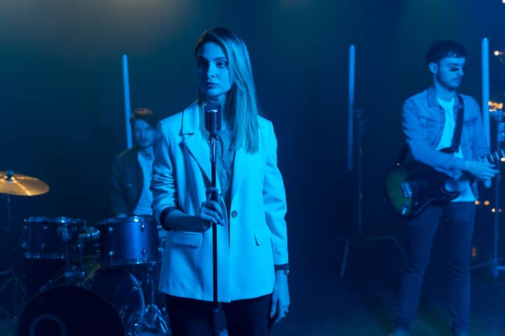 Female singer with band performing on stage under blue lighting, showcasing live music atmosphere.