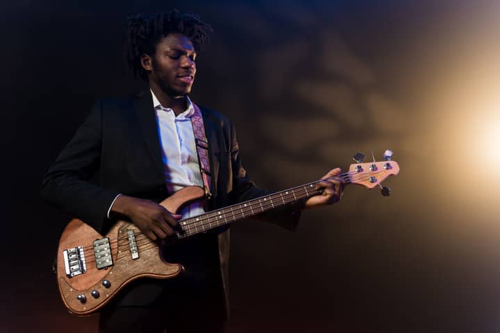A skilled musician in a suit plays an electric bass guitar on stage during a performance.