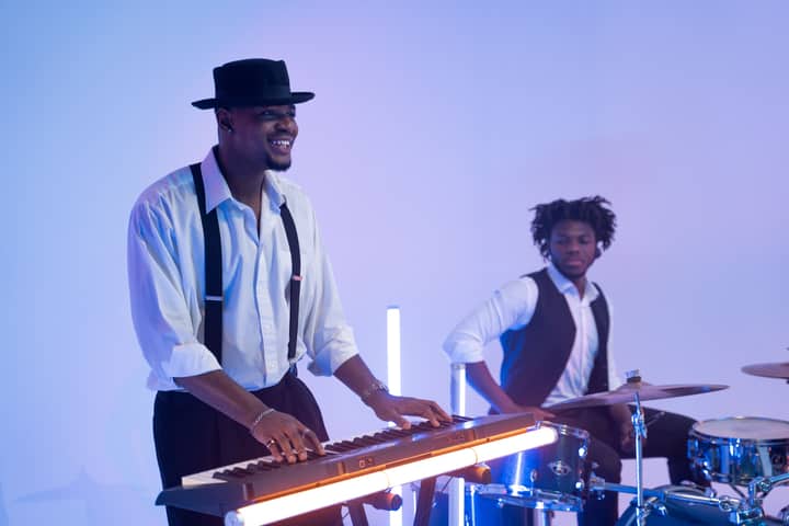 Two musicians playing keyboard and drums in a modern, stylish setting.