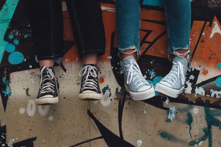 Two pairs of sneakers hanging over a graffiti wall, showcasing urban street style.