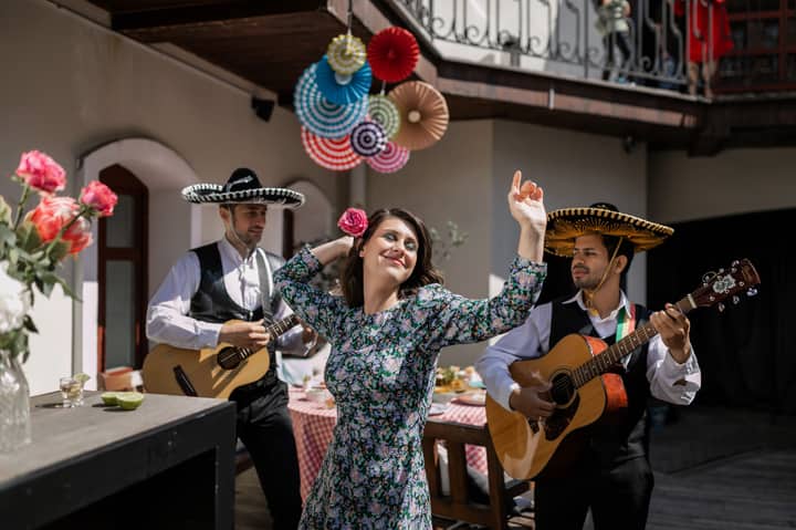 A lively scene with a woman dancing alongside mariachi musicians playing guitars.