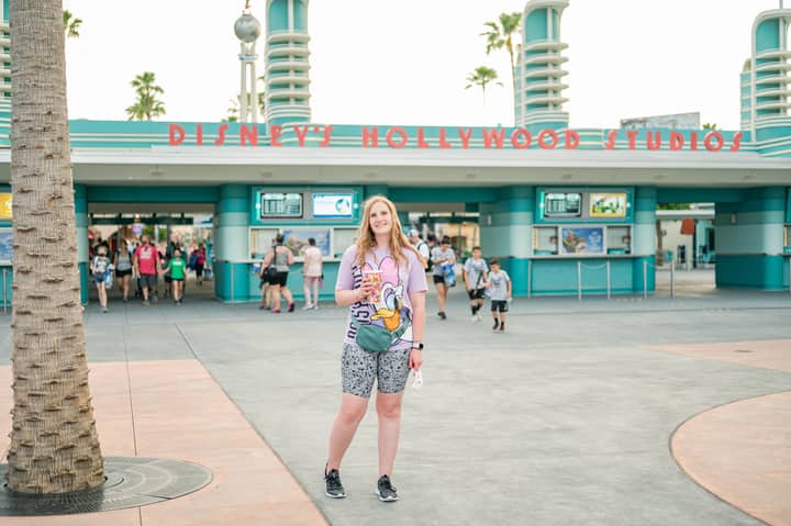 Woman smiling in front of Disney's Hollywood Studios entrance, wearing a Donald Duck shirt.