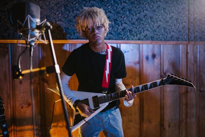 A young adult playing an electric guitar in a cozy indoor studio setting with professional equipment.