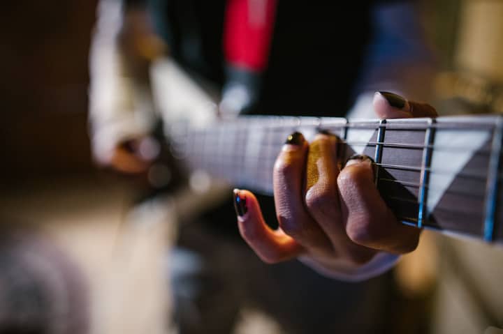 Focused hands of a musician strumming an electric guitar in a dynamic music approach.