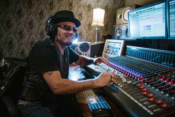 Music producer in a recording studio adjusting sound mixer and smiling at the control panel.