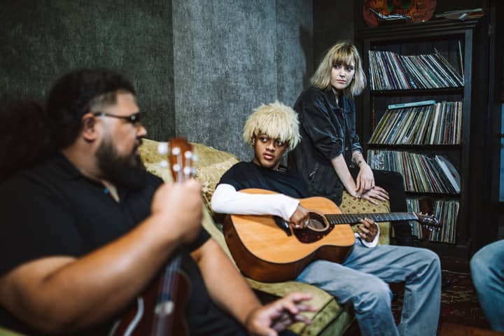 Group of musicians playing guitars and socializing in a cozy indoor space.